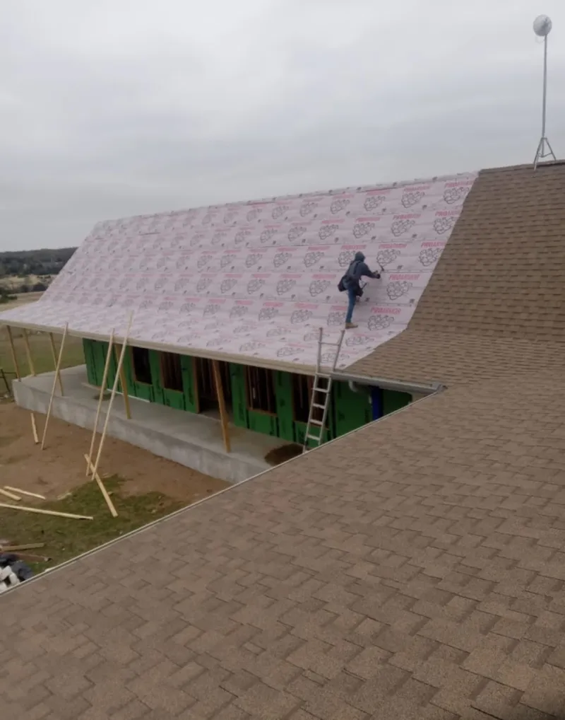Worker preparing underlayment for a metal roof installation in New Windsor